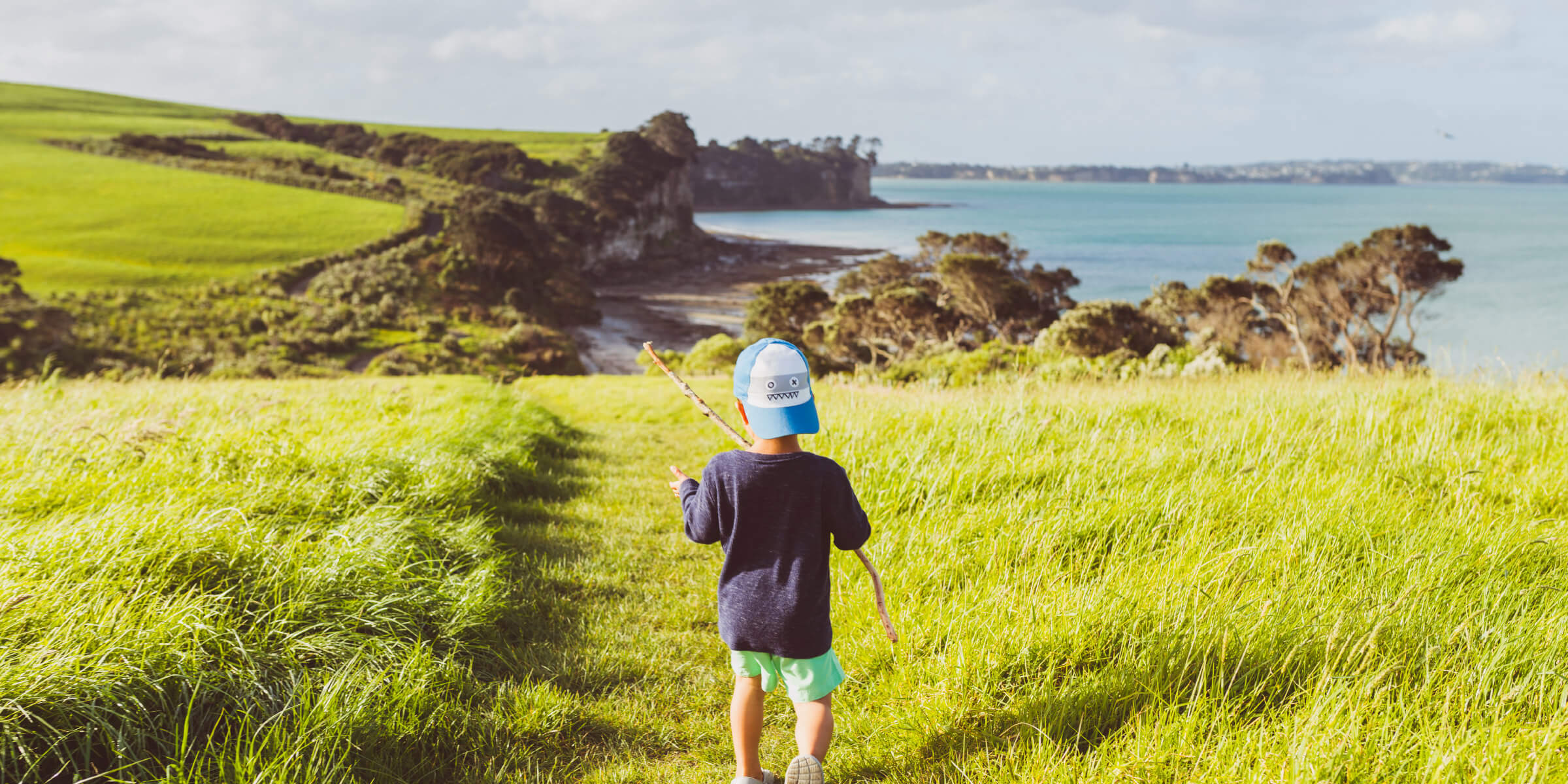 Child walking through park with sea views