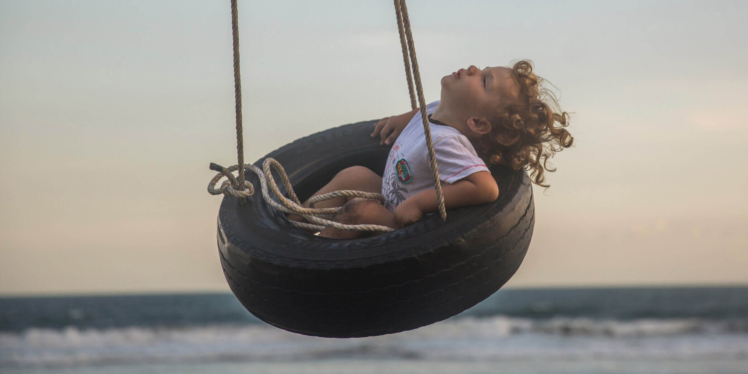 Child on tyre swing at the beach